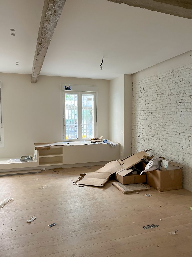 Espacio de comedor de una vivienda con elemento bajo a medida y pared en ladrillo visto blanco